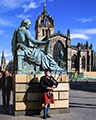 Bagpipper in front of David Hume Statue and St Giles Cathedral in background